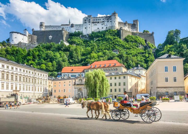 Pferdekutsche in der Stadt Salzburg mit Festung Hohensalzburg im Hintergrund